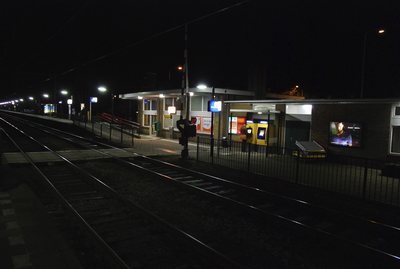 904821 Gezicht op de perronzijde van het N.S.-station Veenendaal-De Klomp te De Klomp (gemeente Ede), bij avond.